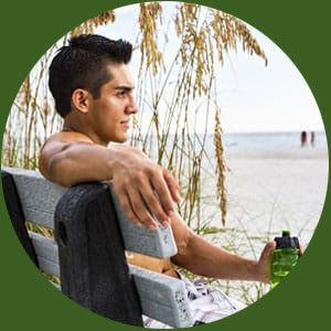 Man Sitting On Beach With Water Bottle